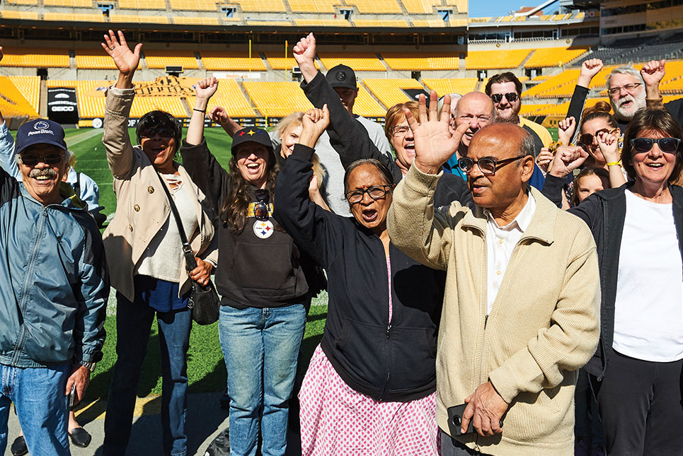 Crowd of Steelers fans cheering on the field during a tour of Acrisure Stadium