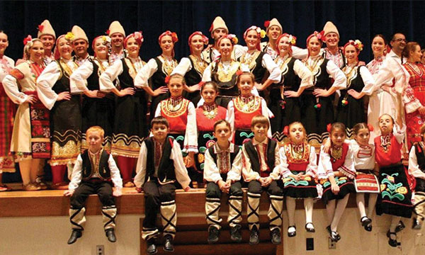 A group of young folk dancers seen standing on stage in Bulgarian folkwear