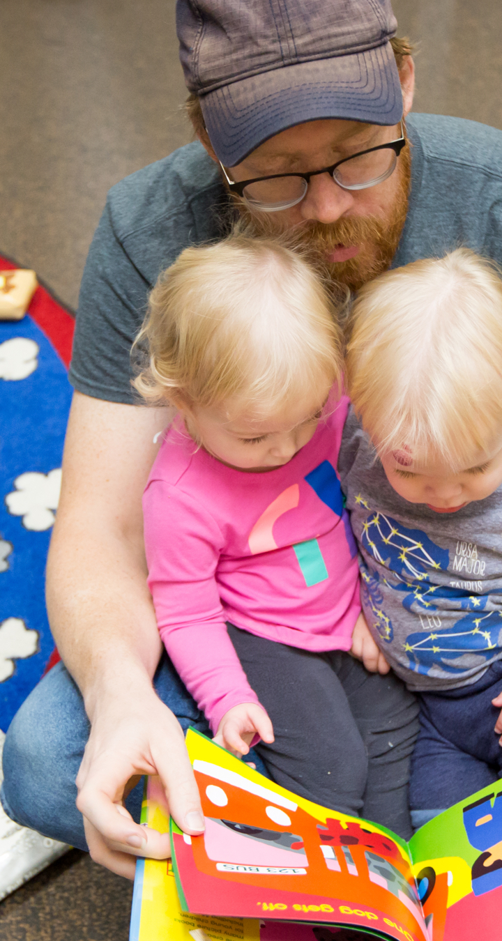 Man and two children reading a book together