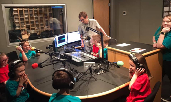 Children sitting around the table of a radio studio