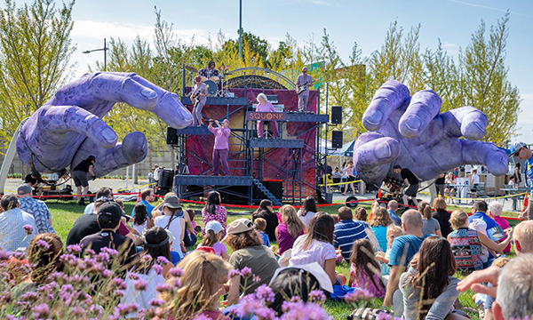 Squonk Opera and its giant purple hands performing in front of an outdoor audience