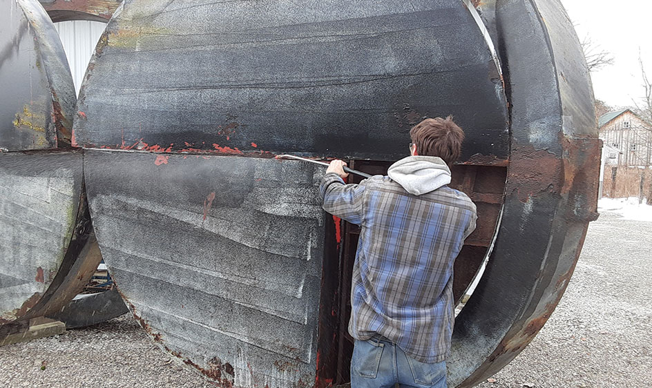 Man works on restoration of a large, circular sculpture.