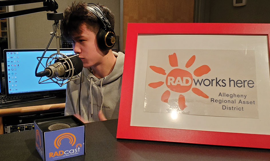 Student podcaster sits at a microphone in SLB Radio's sound studio.