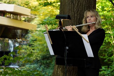 Woman playing a flute at a music stand outdoors at Falling Water.