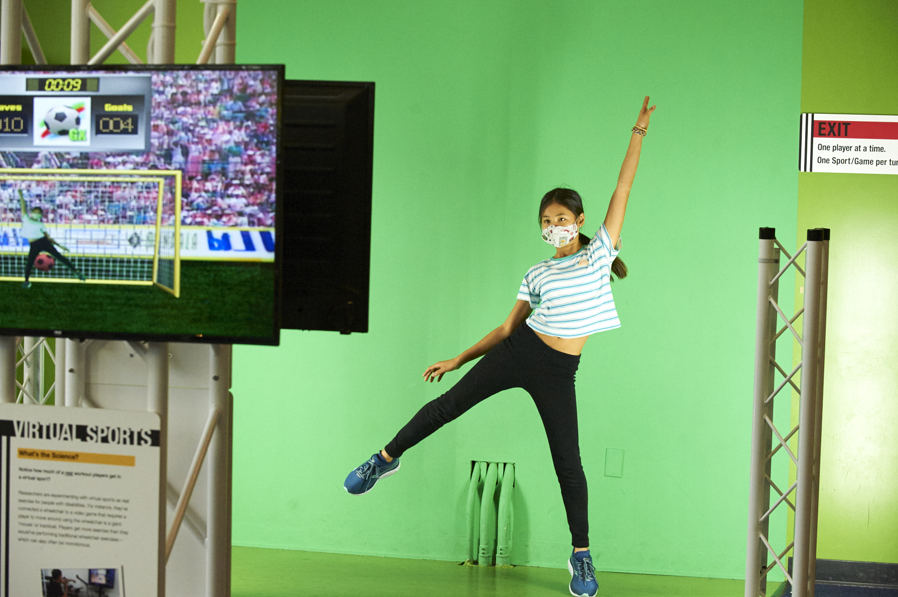 Girl playing virtual soccer in front of a green screen