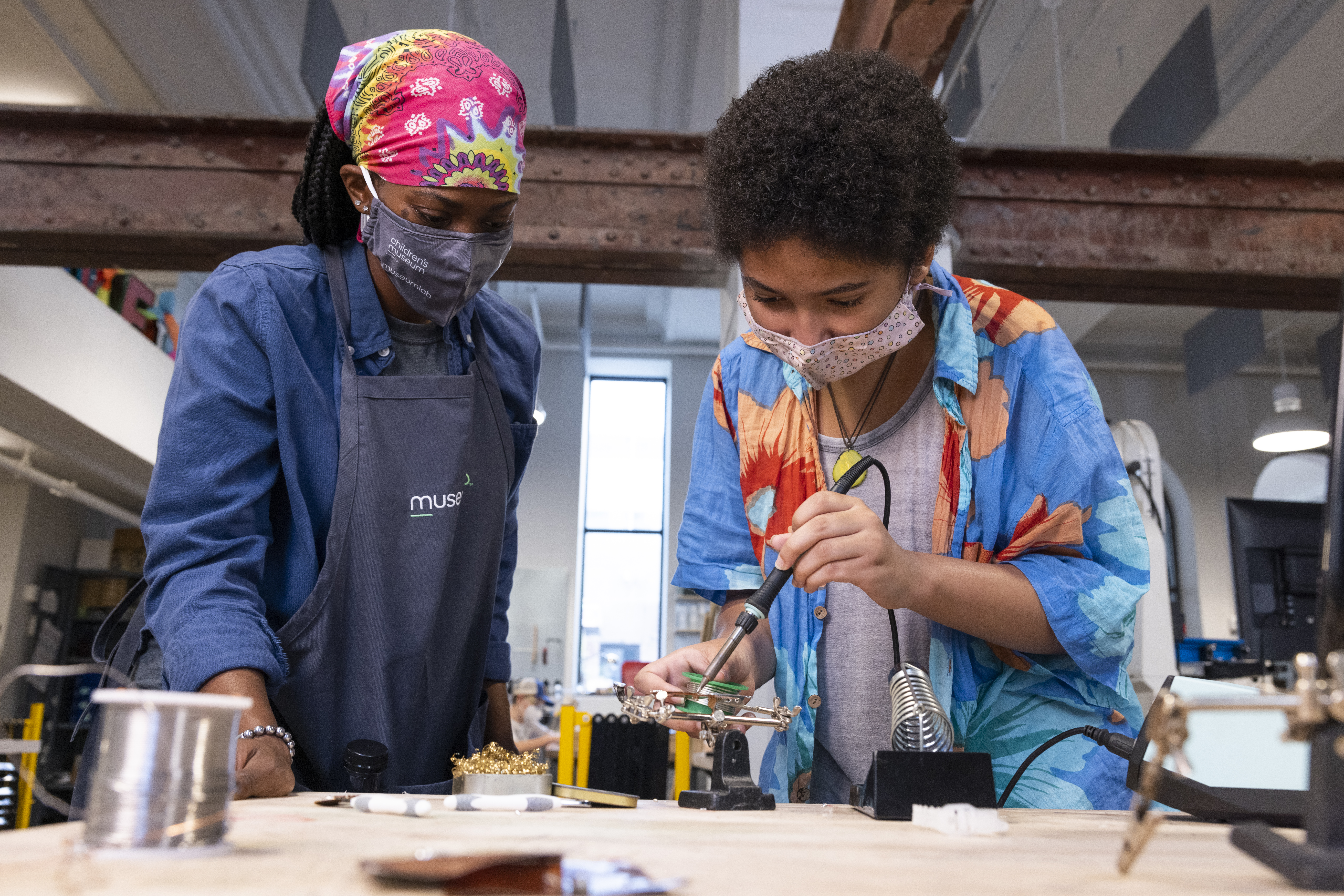 Women and child soldering two metal pieces together.
