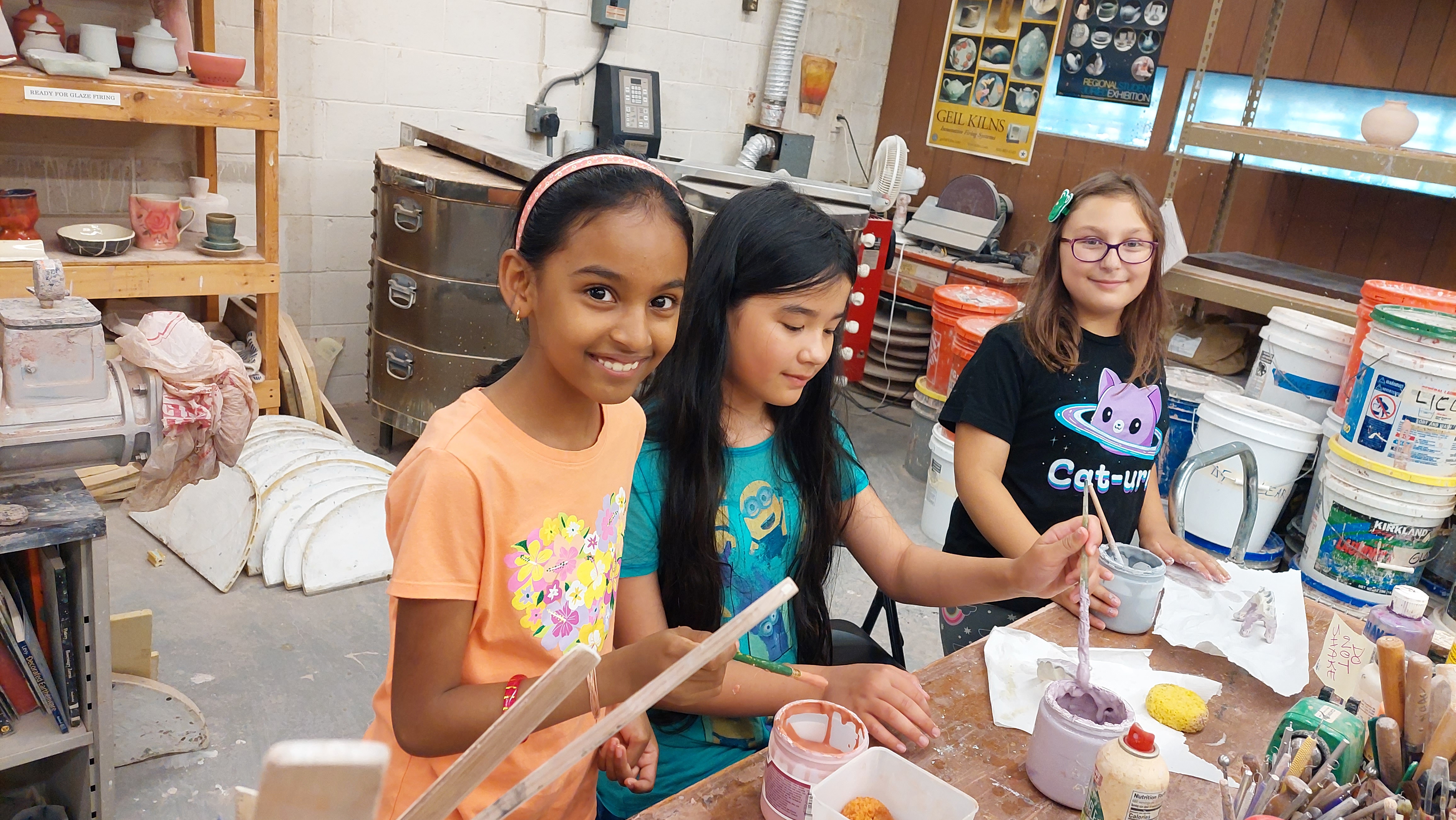 Three children making art and smiling at the camera