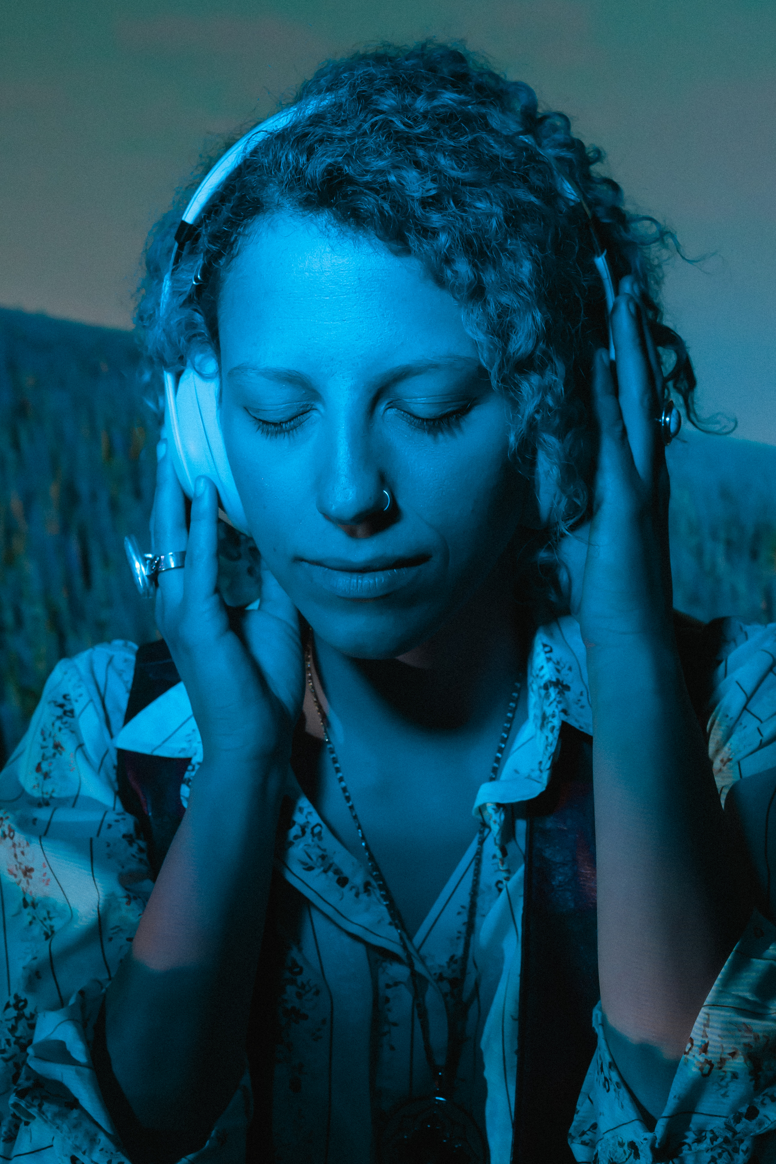 Woman wearing headphones in darkness with blue light