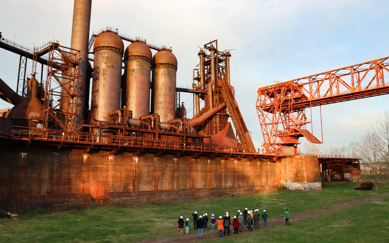 A group of people standing in front of an historic blast furnace