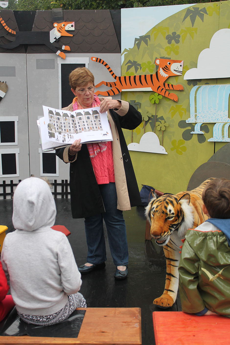 A woman reading a book aloud for a group of children