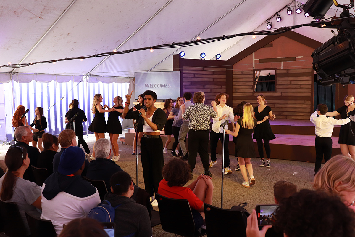 Teens performing songs on a tented stage