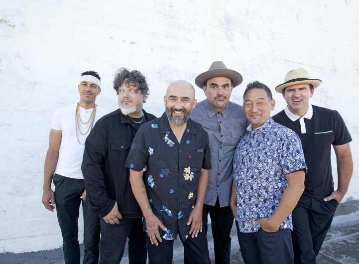 Photograph of band Ozomatli in front of a white wall