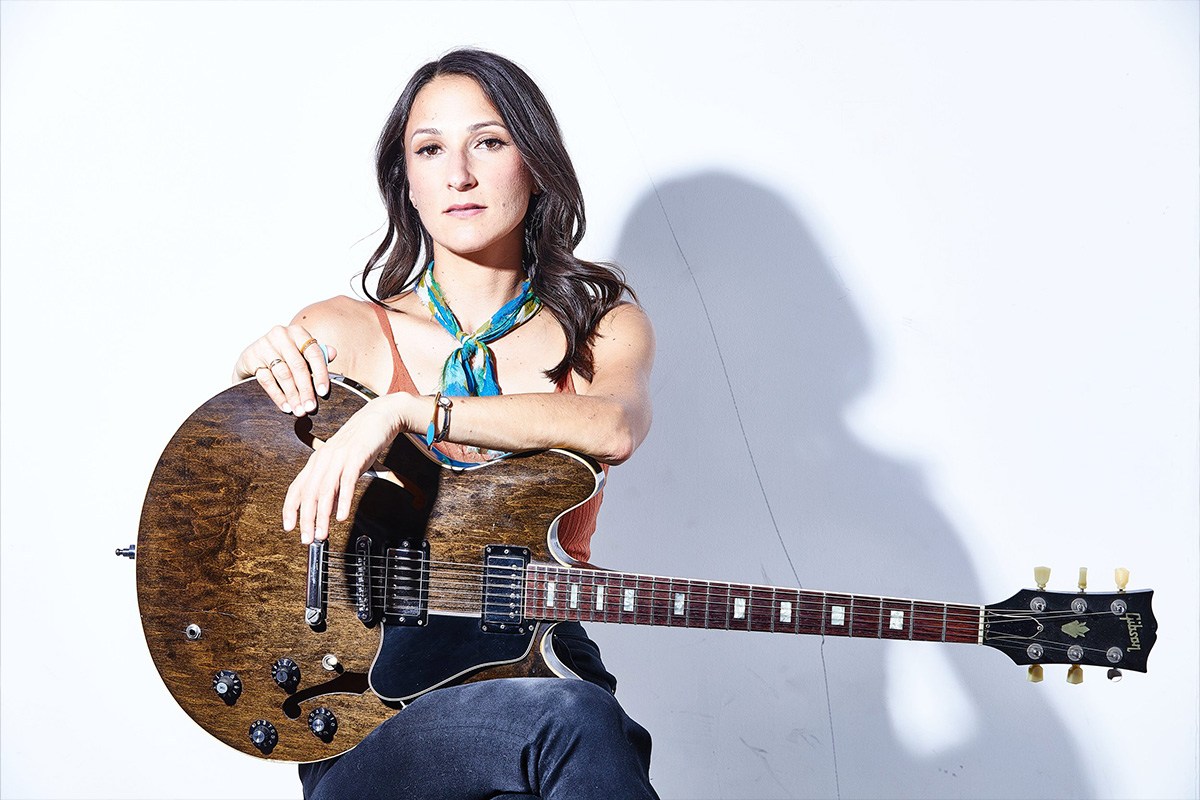 Photograph of Molly Miller posing with an acoustic guitar