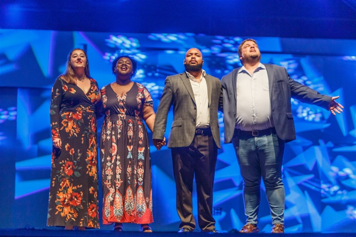 Photo of four young opera singers standing on a stage