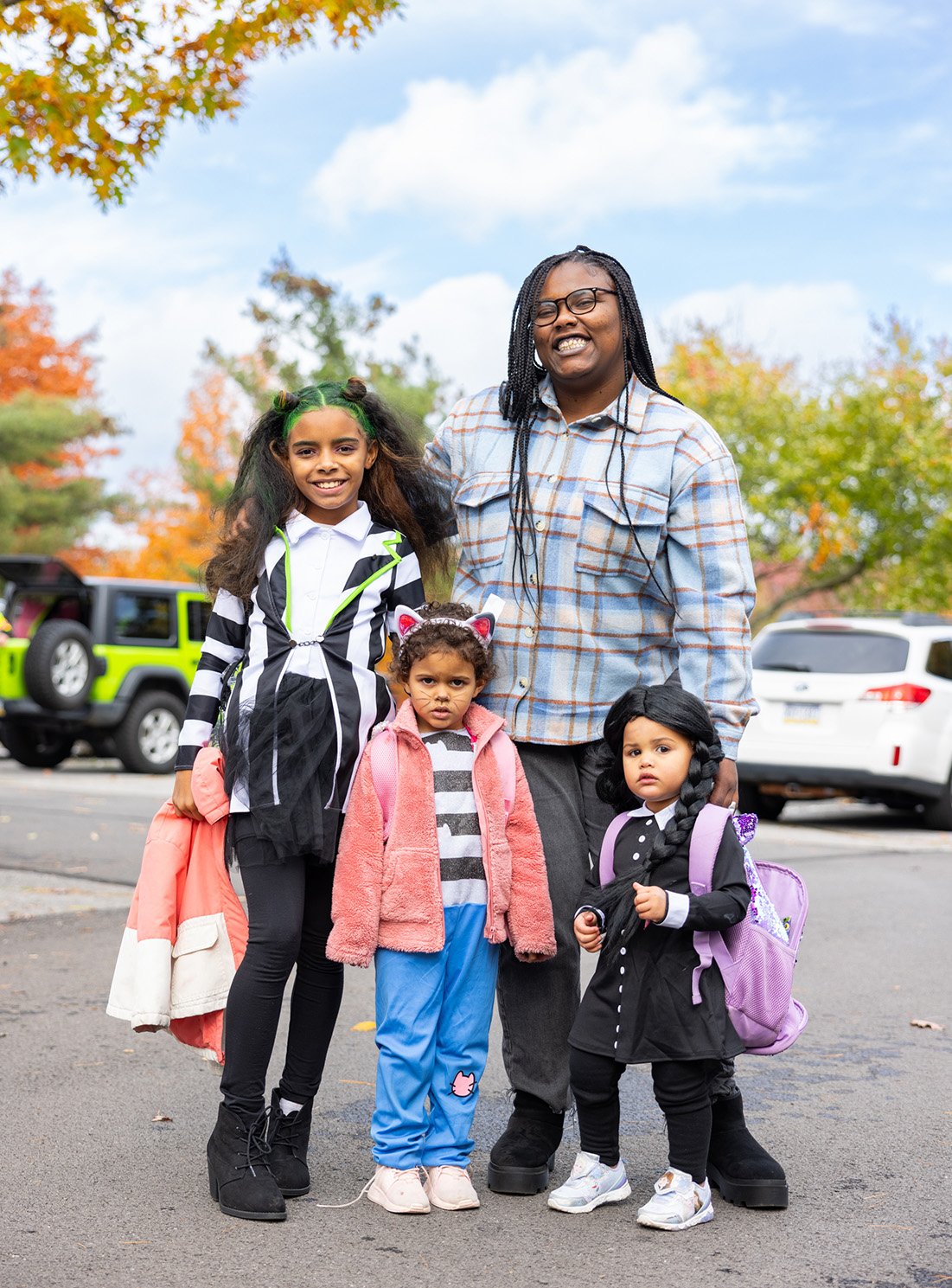 Family dressed up for Halloween standing in front of trees